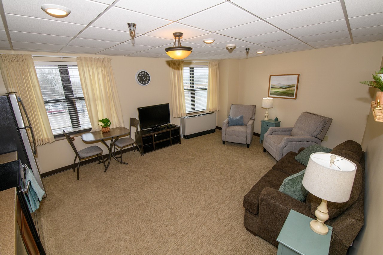 One Bedroom Assisted Living Apartment - Spacious living area with separate bedroom, kitchenette, and comfortable seating